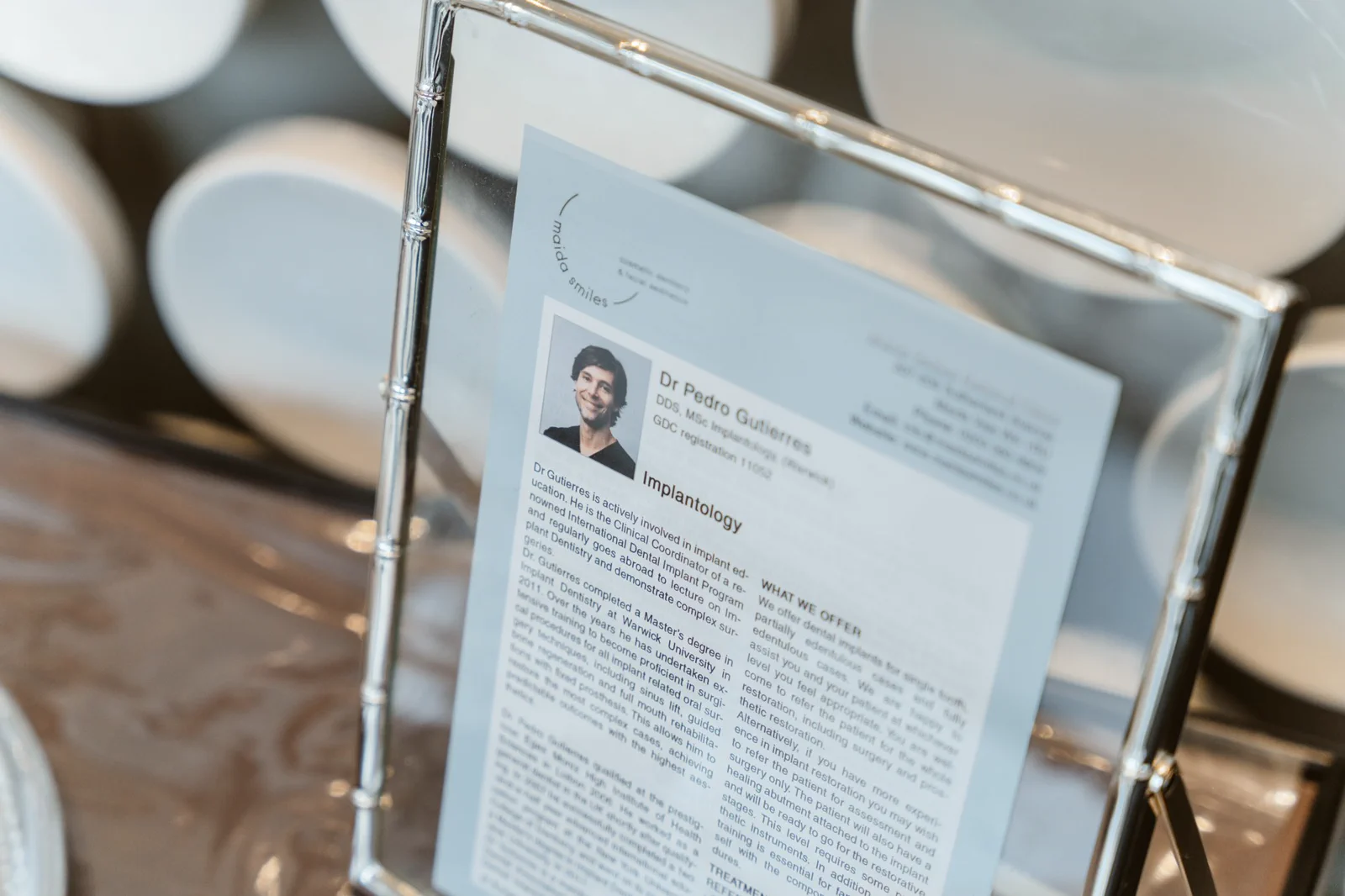 A framed profile card outlines Dr Pedro Gutierres's implantology training and experience.
