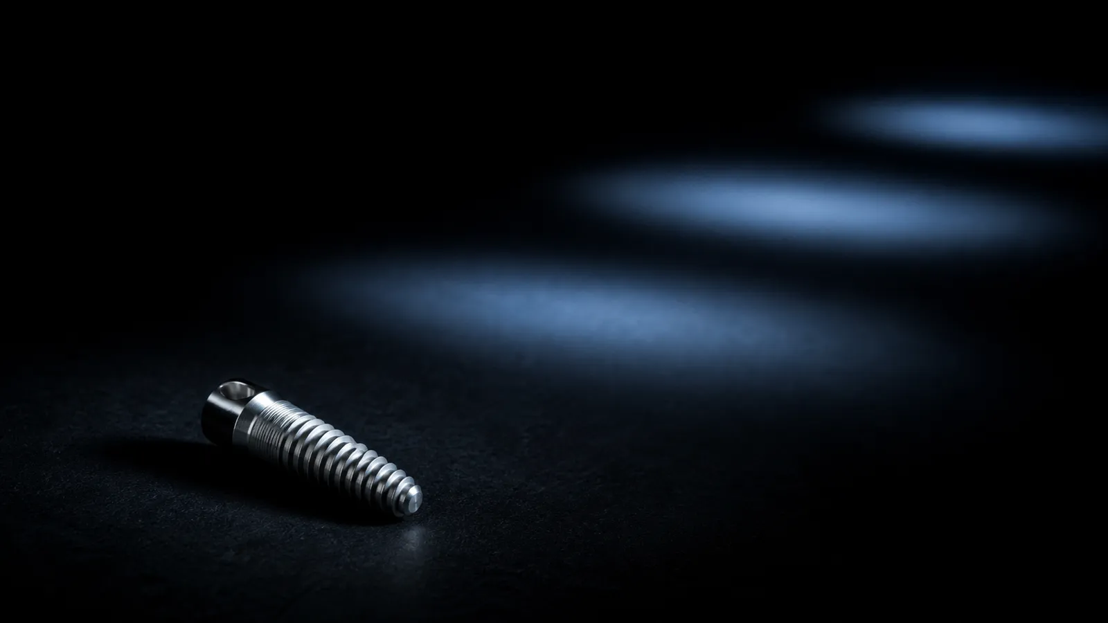 Titanium dental implant beneath three receding pools of cool blue light.