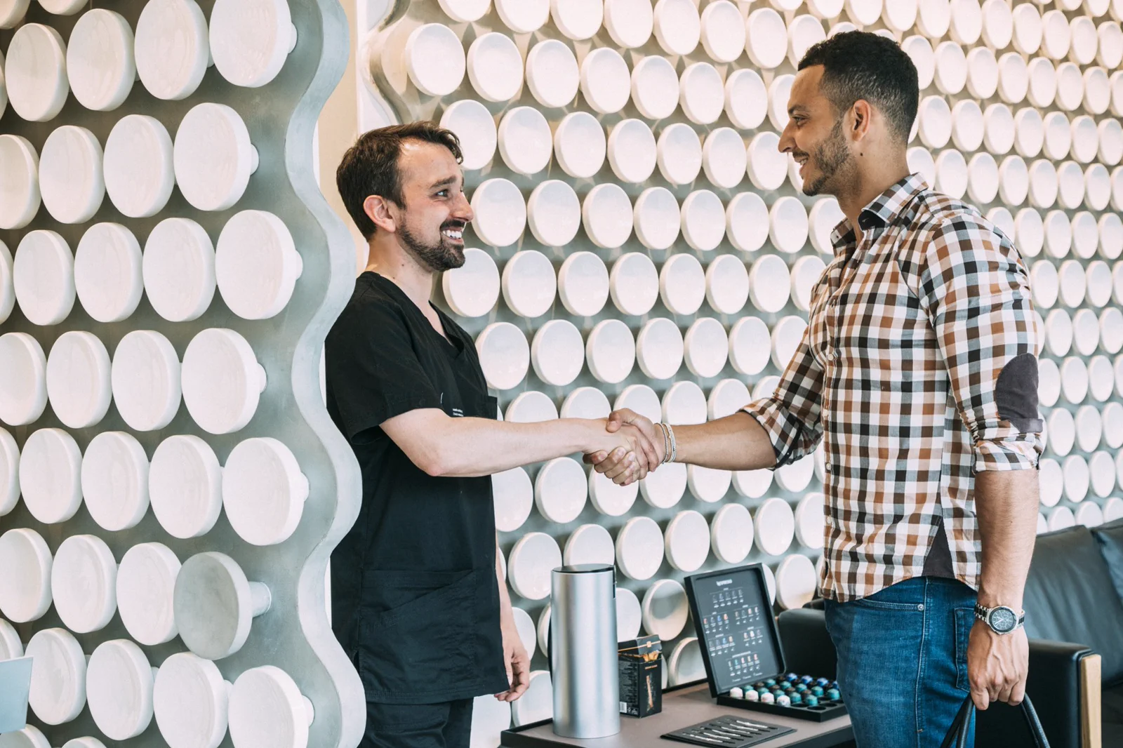 A dentist welcomes a patient with a handshake at the Maida Smiles reception.