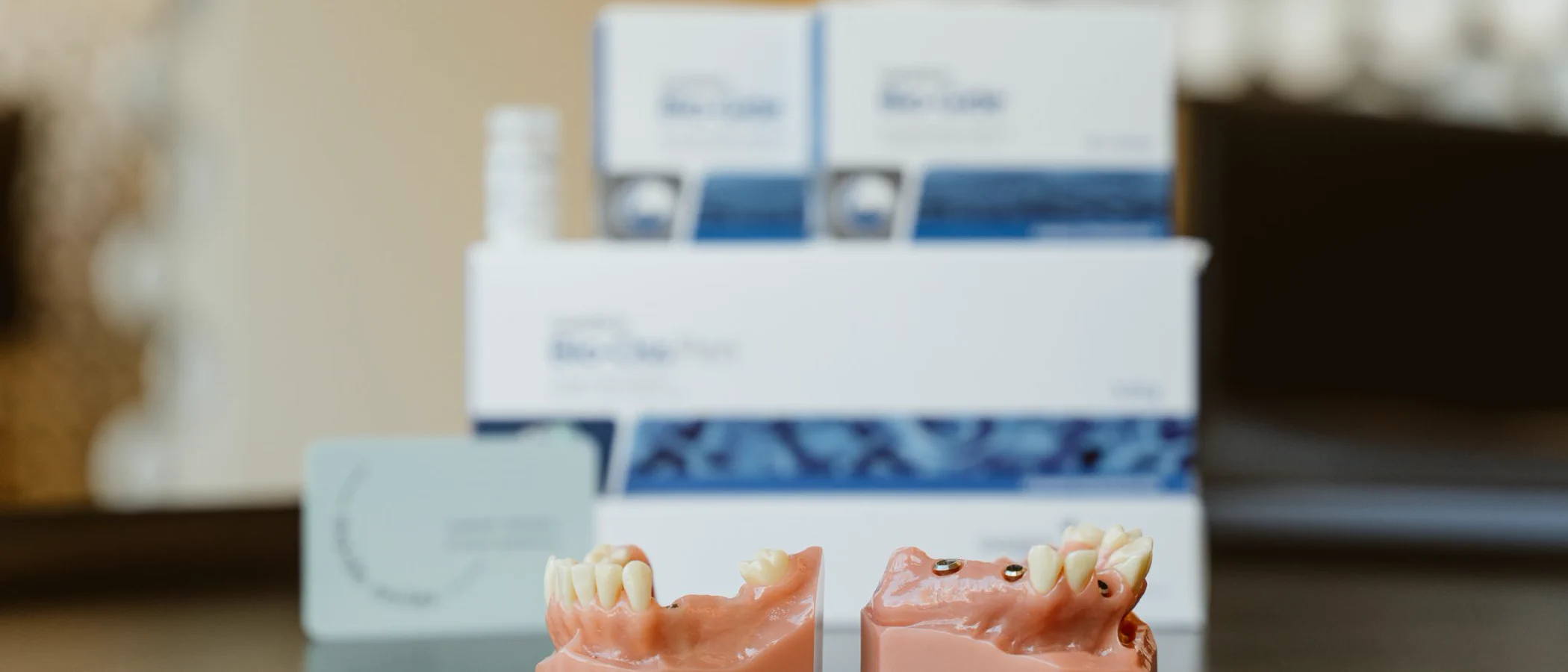 Dental implant models sit beside bone regeneration materials on a clinic desk.