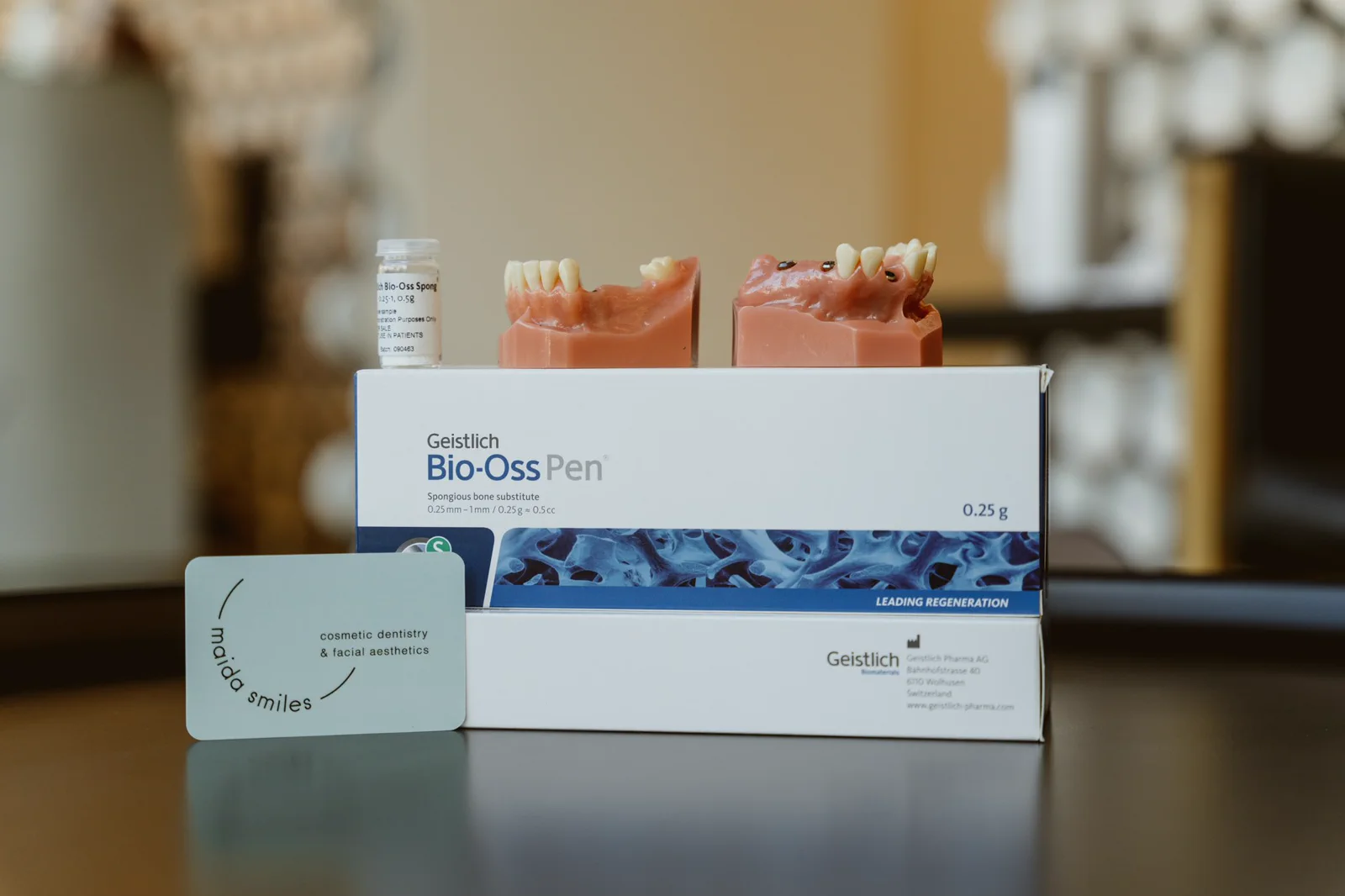 A bone regeneration kit is displayed with dental implant models at Maida Smiles.